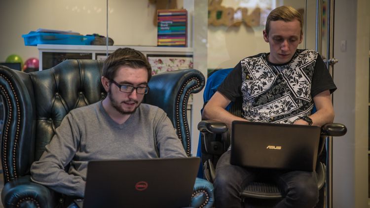 Two developers working on laptops in an office